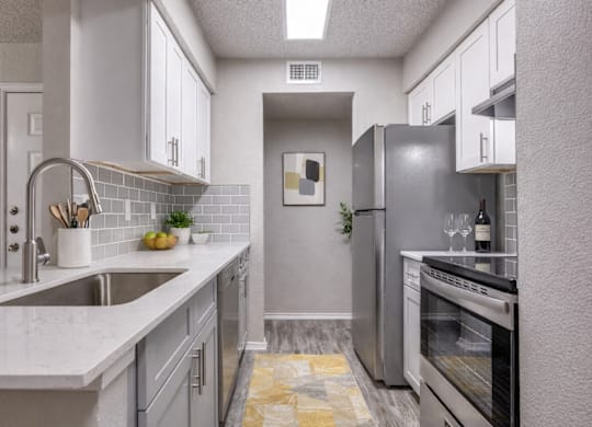 A kitchen with a sink, refrigerator, and oven.