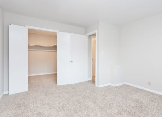 a bedroom with a closet and a carpeted floor
