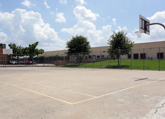 A basketball court with a basketball hoop and a fence surrounding it.