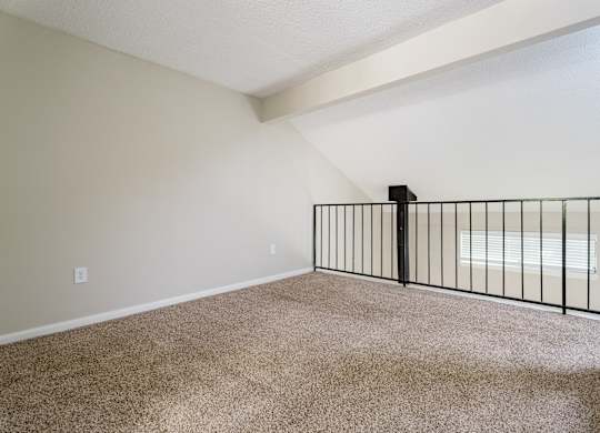 Empty room with carpeted floor and a black railing. at Rosen at North Hills, Raleigh