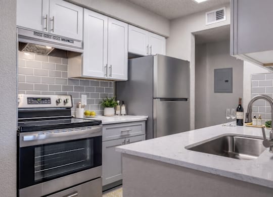 A modern kitchen with a stainless steel refrigerator, oven, and sink.
