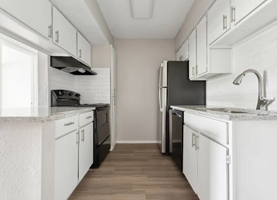 A kitchen with white cabinets and a black refrigerator.