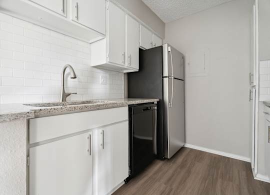 A kitchen with white cabinets and a black fridge. at Anson at North Hills, Raleigh