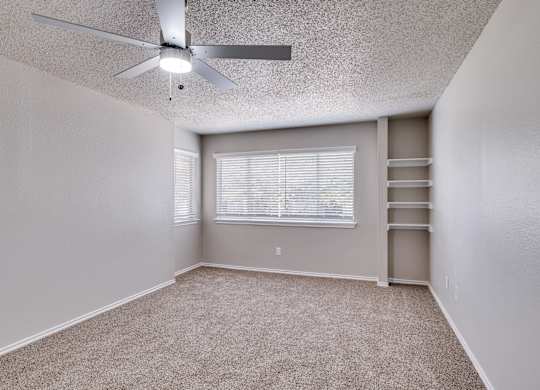 A room with a ceiling fan and a window with blinds.