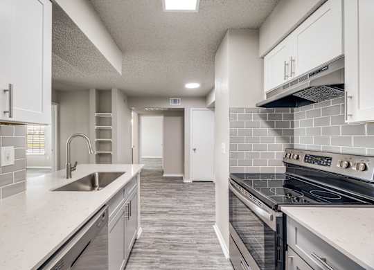 A modern kitchen with white cabinets and a tiled backsplash.