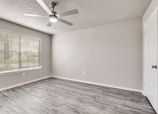 A room with a ceiling fan and a window with blinds.