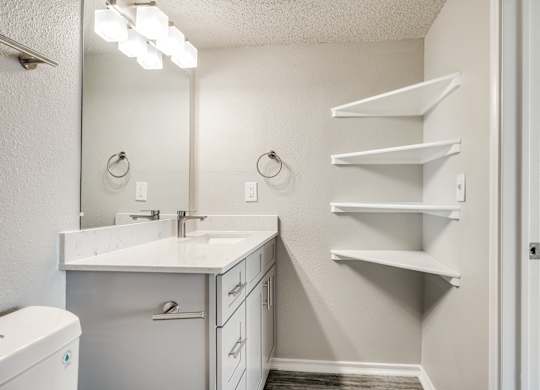 A bathroom with a white counter top and a mirror above it.