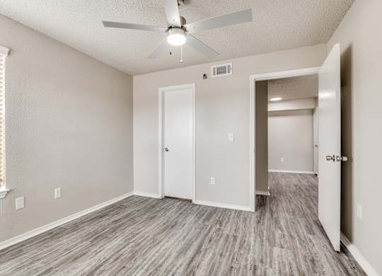 A room with a ceiling fan and two doors.