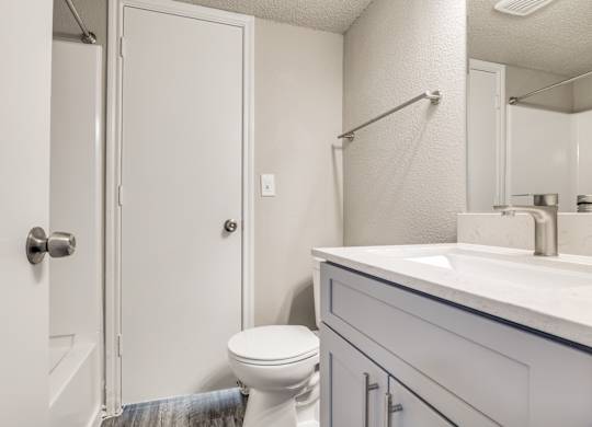 A white bathroom with a toilet, sink, and shower.