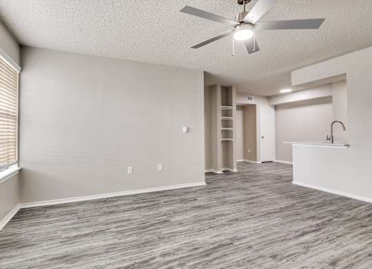 A room with a ceiling fan and wooden flooring.