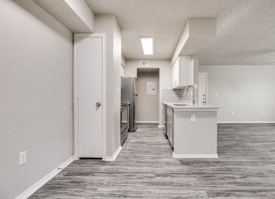 A kitchen area with a refrigerator, sink, and cabinets.