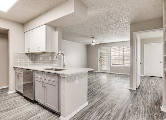 A kitchen with a sink, cabinets, and a window.