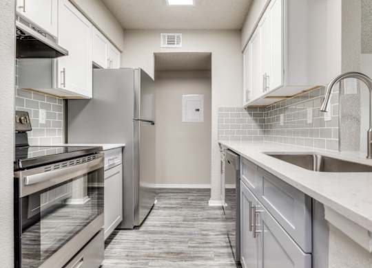 A kitchen with a white tile backsplash and a white sink.