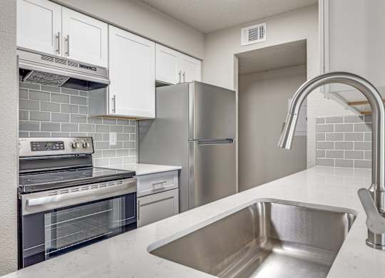 A modern kitchen with a stainless steel sink and refrigerator.