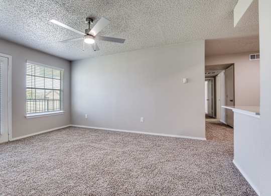 A room with a ceiling fan and carpeted floor.