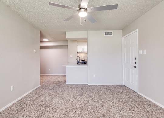A spacious room with a ceiling fan and a carpeted floor.