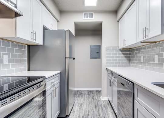 A modern kitchen with a stainless steel refrigerator and white cabinets.