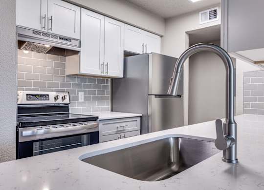 A modern kitchen with a stainless steel sink and refrigerator.