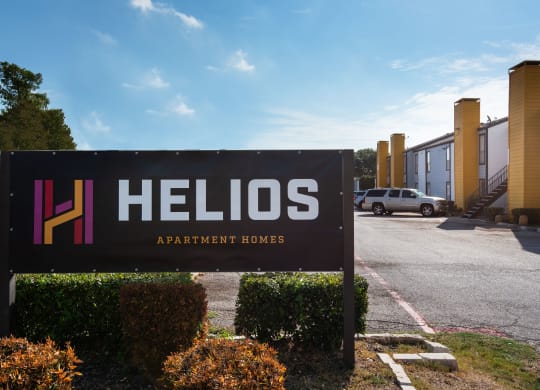 a sign for hellos apartments in front of a parking lot at Helios, Dallas, TX