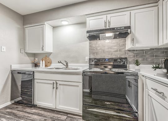 Updated kitchen with electric range and hood at Northwood Heights Apartments, Dallas, TX