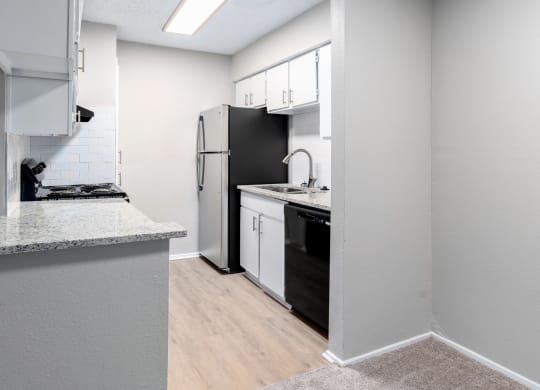 an empty kitchen with white appliances and a black refrigerator