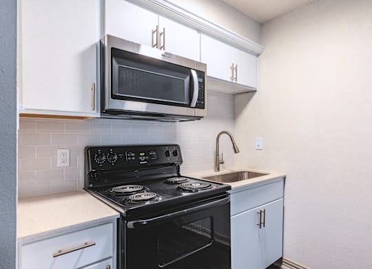 an empty kitchen with a stove and a sink and a microwave