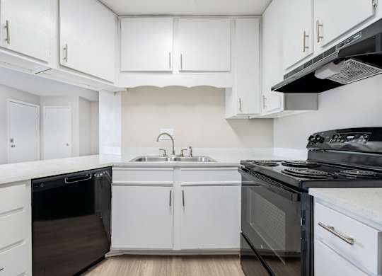 A kitchen with white cabinets and black appliances.