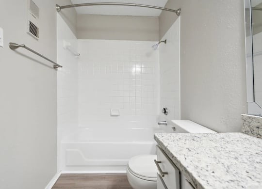 A white bathroom with a toilet, sink, and shower.