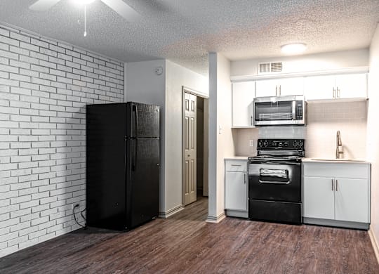 an empty kitchen with white appliances and a black refrigerator
