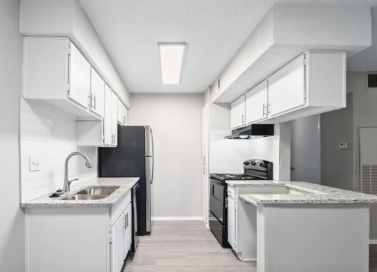 an empty kitchen with white cabinets and a black refrigerator and sink