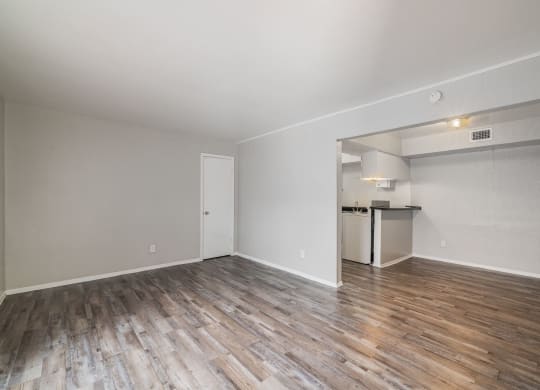 the living room of an apartment with wood flooring and a kitchen at Lumina, Texas