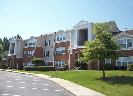 Apartment building with a parking lot in front.