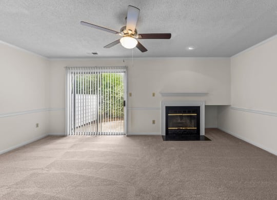 living room with a fireplace, ceiling fan, and large window at Rosewood at Colony Square, Rocky Mount, North Carolina