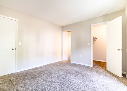 A large, empty room with carpeted floor and white walls.