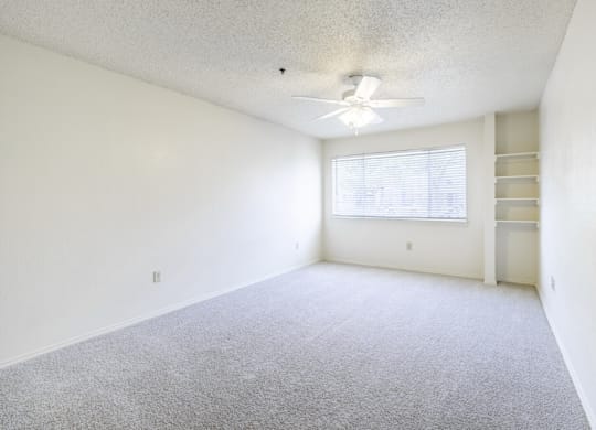 A room with a ceiling fan and a window with blinds.