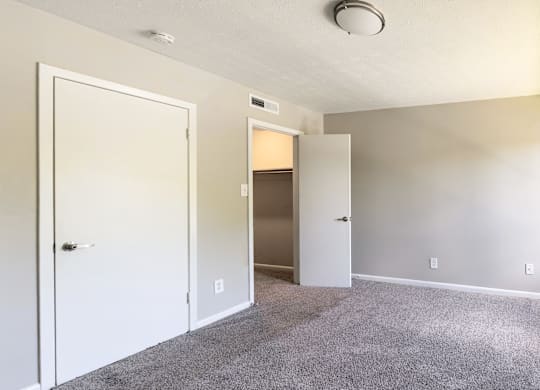 A room with a white door and carpeted floor.