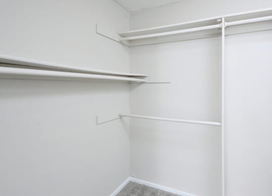 a walk in closet with white walls and white shelves and a white