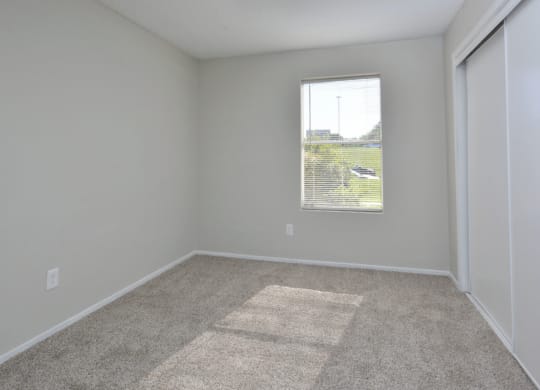 an empty room with a window and carpet