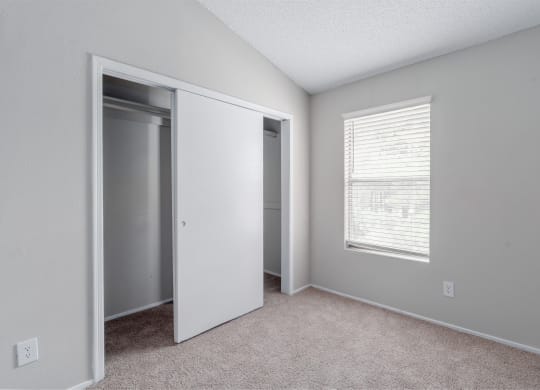 an empty bedroom with a closet and a window