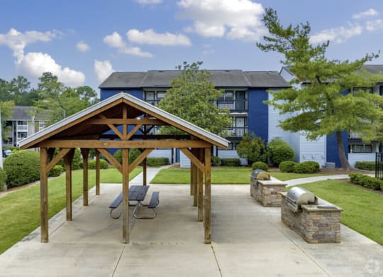 an outdoor pavilion with grills in front of anson at north hills apartments in raleigh nc