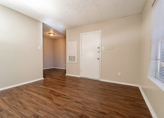 an empty living room with wood flooring and a window