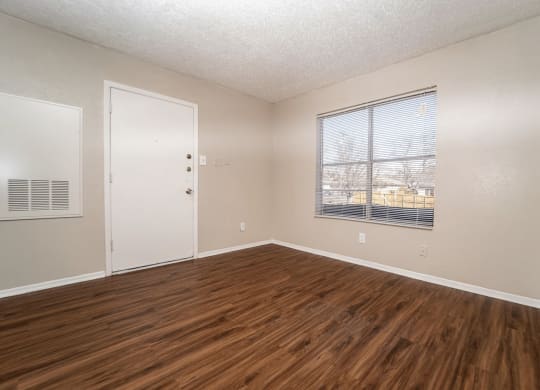 an empty living room with wood flooring and a window