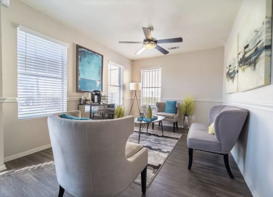 a living room with chairs and a ceiling fan