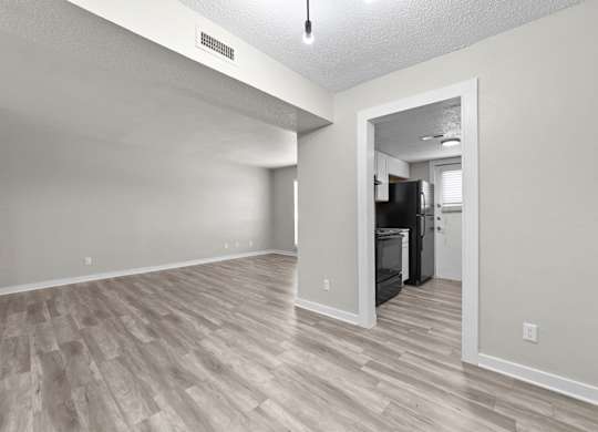 A kitchen area with a refrigerator and oven is visible through an open door.