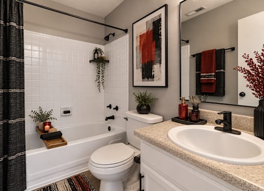 A bathroom with a white toilet, a bathtub with a black shower curtain, and a sink with a black faucet.