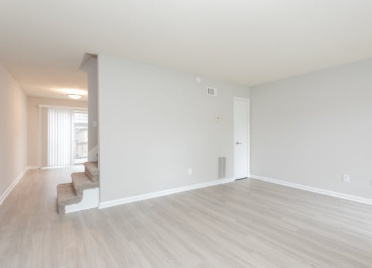 an empty living room with white walls and wood flooring