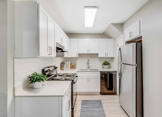 a white kitchen with white cabinets and a stainless steel refrigerator