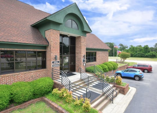 the front of a brick building with stairs and a parking lot
