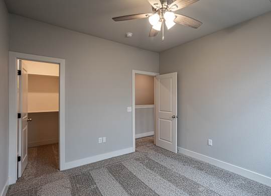 A room with a ceiling fan and two doors at Cedar Crest Apartments, Farmington 72730