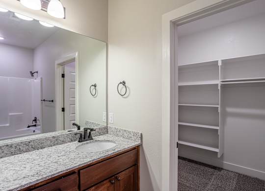 A bathroom with a sink, mirror, and a closet at Cedar Crest Apartments, Arkansas